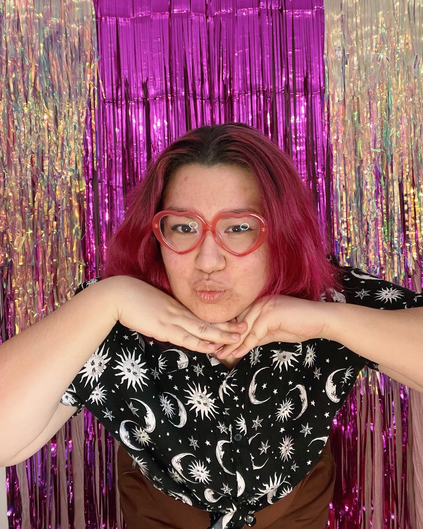 pamela leans towards the camera with her head resting on her hands and a fun kissy face